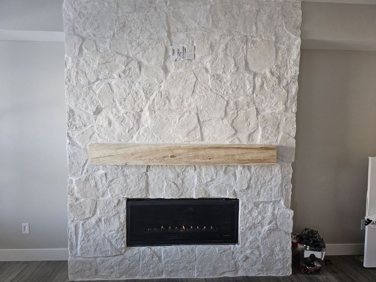 A hand-hewn Douglas Fir mantel installed above a modern fireplace with a white stone surround
